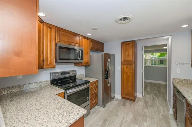 a kitchen with stainless steel appliances granite countertop a refrigerator stove and sink