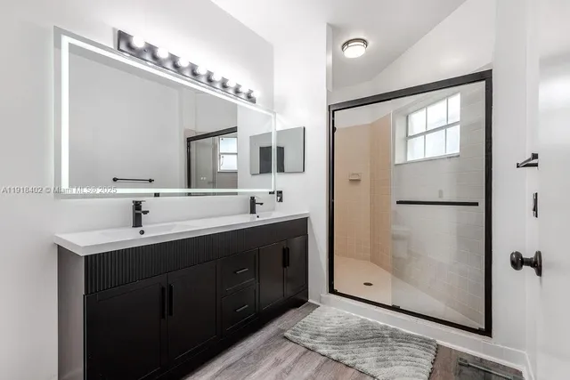 a bathroom with a double vanity sink mirror and shower