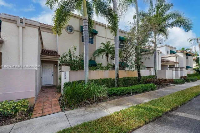 a view of a house with a yard and palm trees