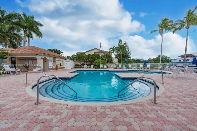 a view of swimming pool with lawn chairs and plants