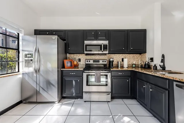 a kitchen with stainless steel appliances granite countertop a refrigerator and a stove top oven