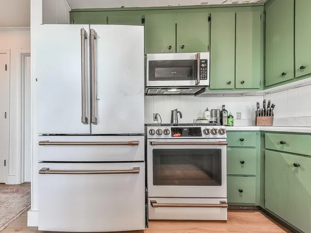 a kitchen with stainless steel appliances white cabinets and a refrigerator