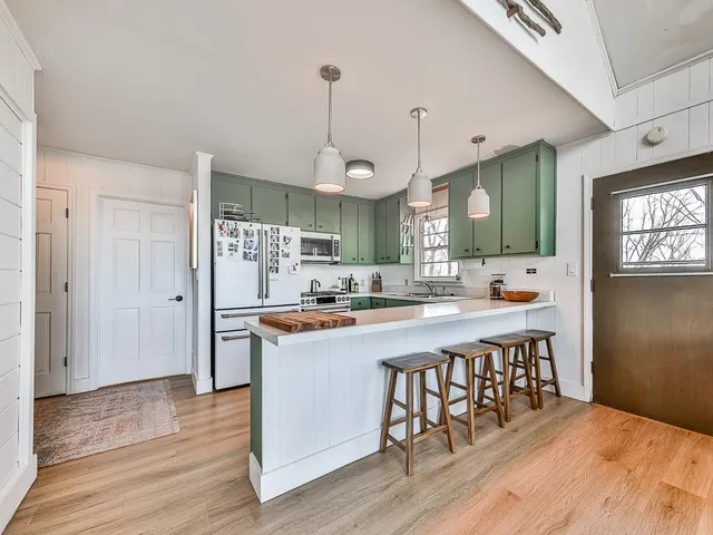 a kitchen with stainless steel appliances a dining table chairs stove and cabinets