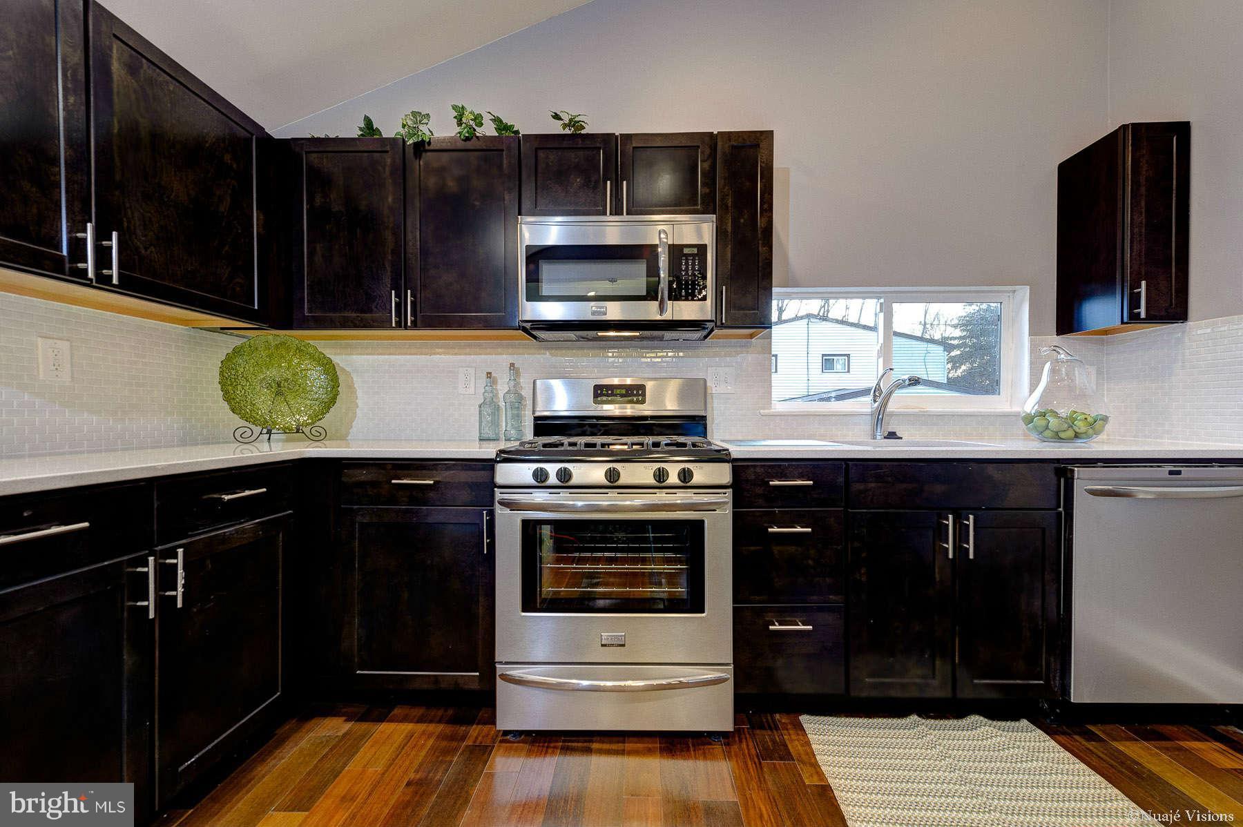 835 Milford Mill Road Baltimore, MD 21208 - Photo 13 of 30 a kitchen with stainless steel appliances a stove a microwave and cabinets