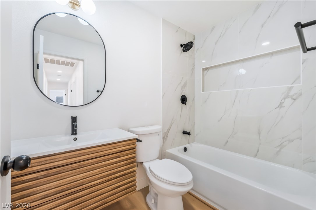 668 Rising Brook Drive Henderson, NV 89011 - Photo 15 of 22 A well-appointed bathroom with a sleek wooden vanity and marble-inspired tile.