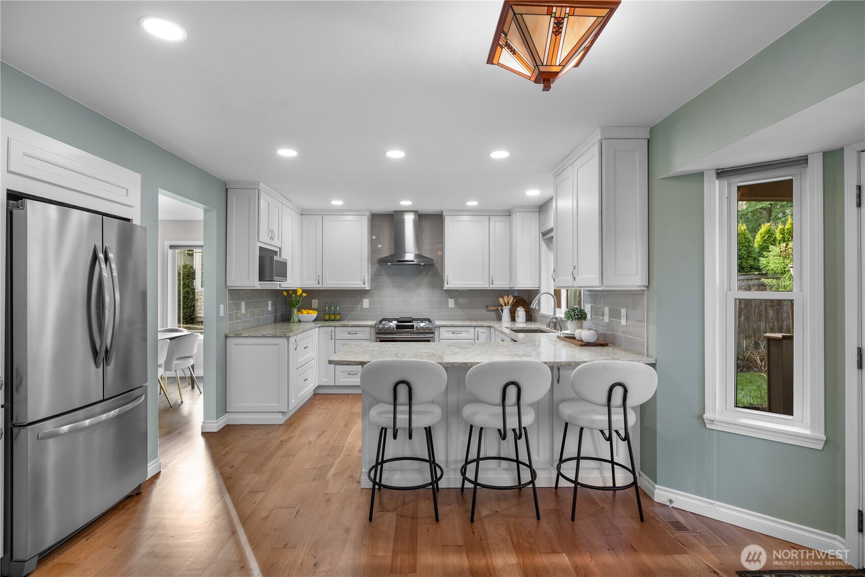 12103 Northeast 168th Place Bothell, WA 98011 - Photo 7 of 36 a kitchen with a refrigerator a stove a sink and white cabinets with wooden floor