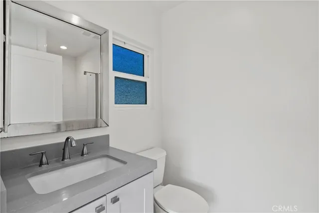 a bathroom with a toilet sink vanity and mirror