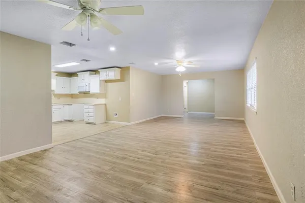 a view of an empty room and a kitchen