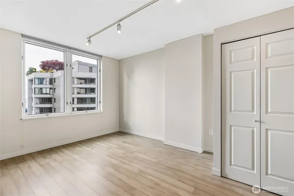 a view of an empty room with a window and wooden floor