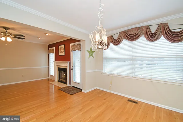 a view of a room with wooden floor and a chandelier fan