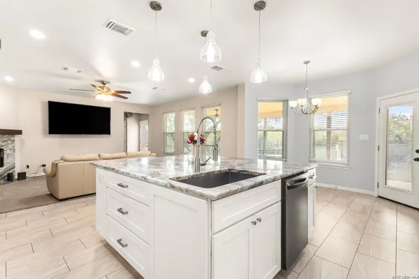 a kitchen with a stove a sink and a flat screen tv
