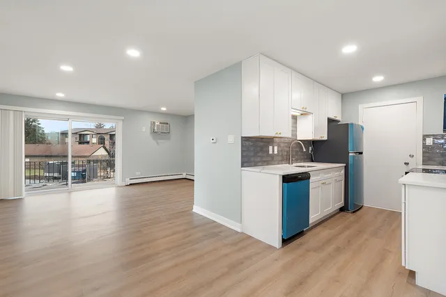 a kitchen with a refrigerator and a wooden floor