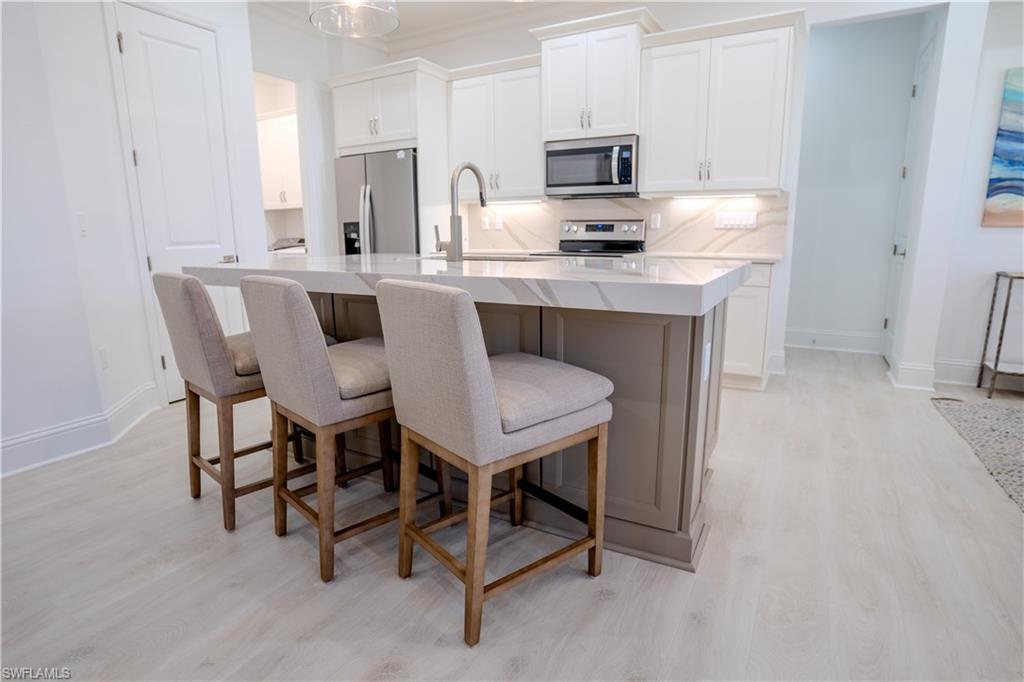 7150 Saona Court Naples, FL 34113 - Photo 12 of 31 a kitchen with kitchen island granite countertop a sink cabinets a counter top space and stainless steel appliances