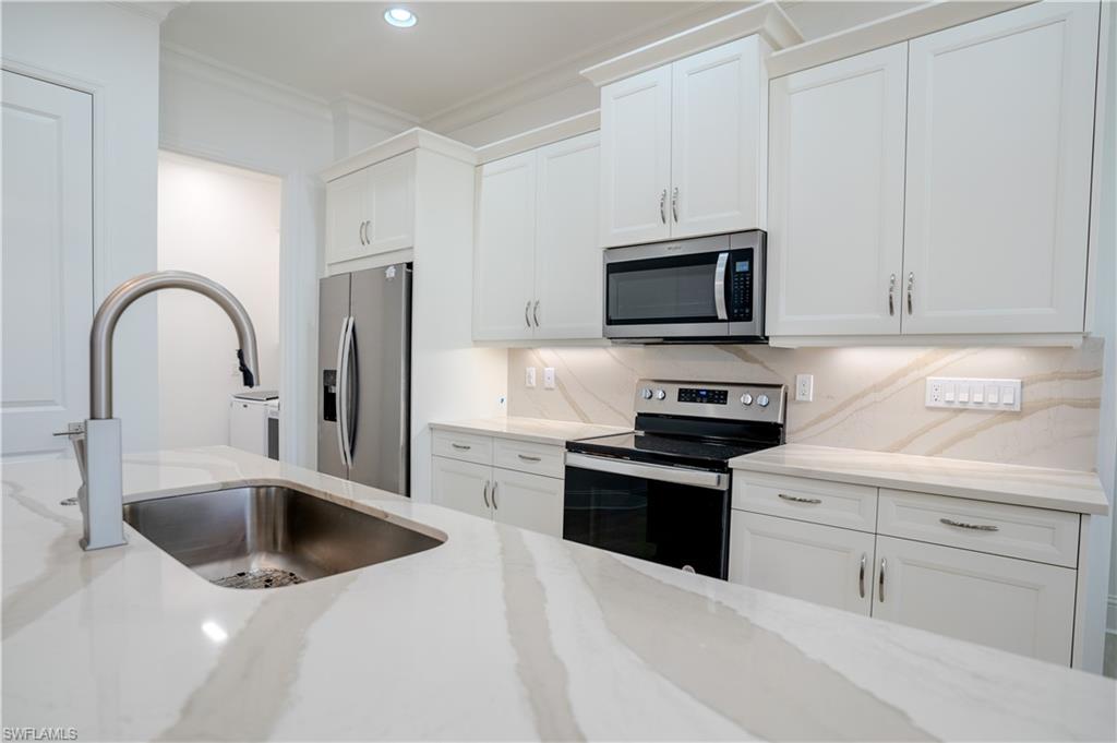 7150 Saona Court Naples, FL 34113 - Photo 13 of 31 a kitchen with stainless steel appliances granite countertop a stove a sink and a microwave