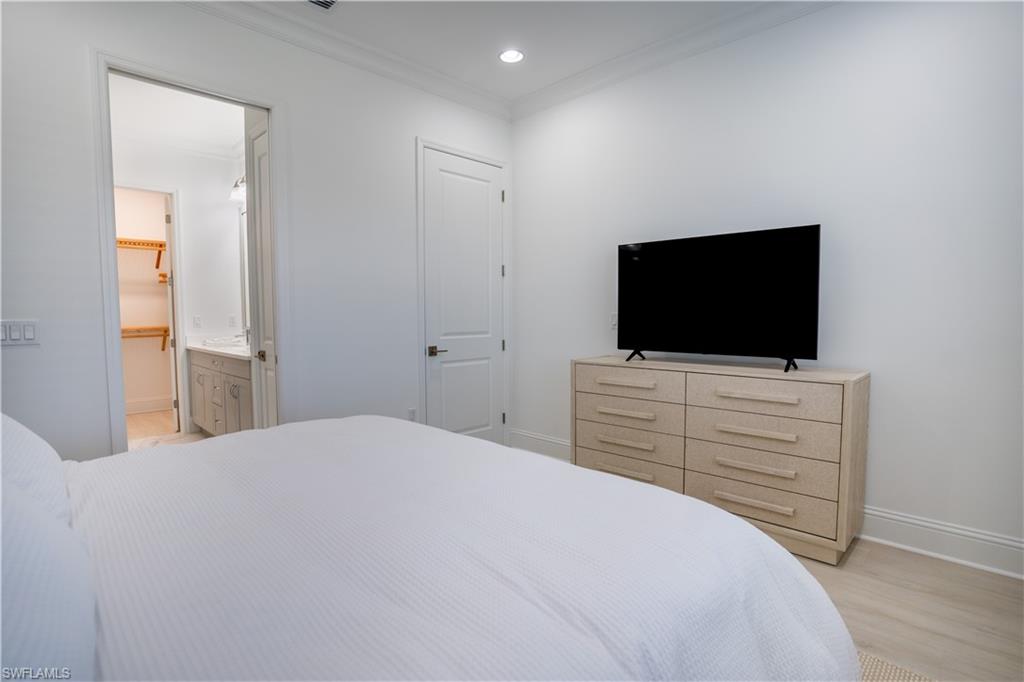 7150 Saona Court Naples, FL 34113 - Photo 6 of 31 a bedroom with a bed and a flat screen tv in white walls