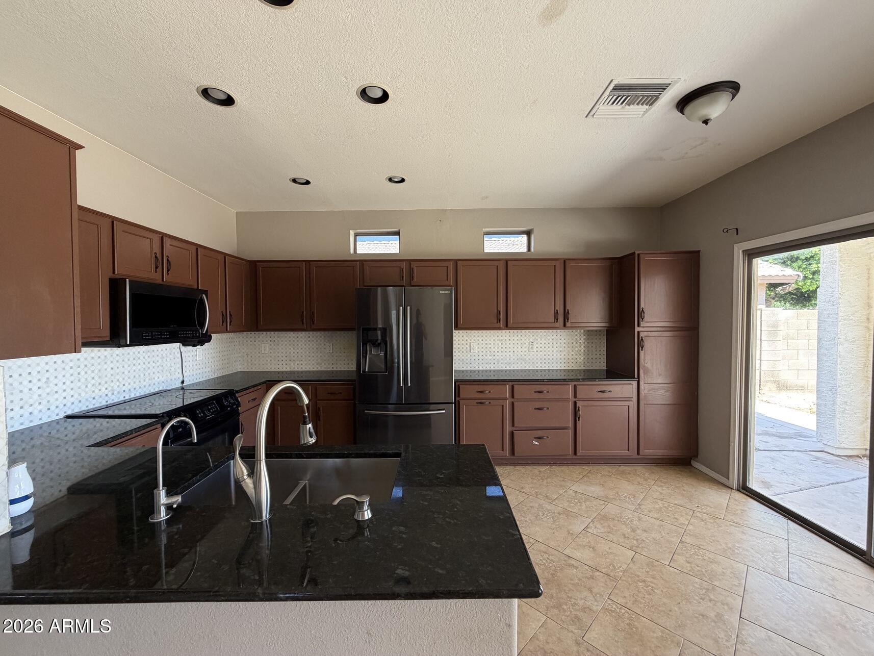 10807 West Monte Vista Road Avondale, AZ 85392 - Photo 12 of 33 a kitchen with stainless steel appliances granite countertop a refrigerator a sink dishwasher a stove and a refrigerator with wooden floor