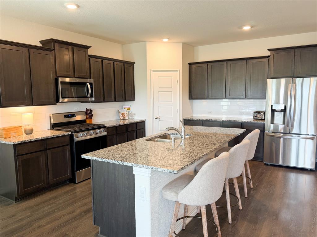 929 Philadelphia Street Fate, TX 75189 - Photo 8 of 34 a kitchen with kitchen island granite countertop a sink and stainless steel appliances