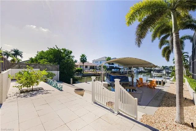 a view of a patio with couches table and chairs under an umbrella with a barbeque