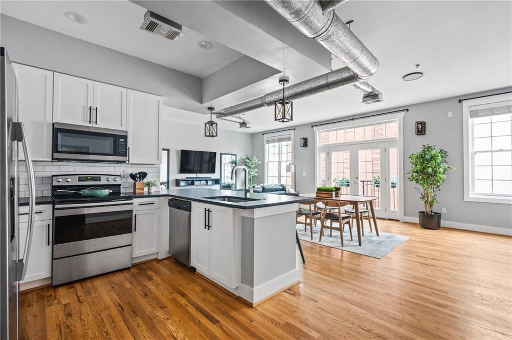 1029 Piedmont Avenue Northeast, Unit 303 Atlanta, GA 30309 - Photo 11 of 44 a kitchen with stainless steel appliances granite countertop a stove top oven a sink dishwasher a dining table and chairs with wooden floor