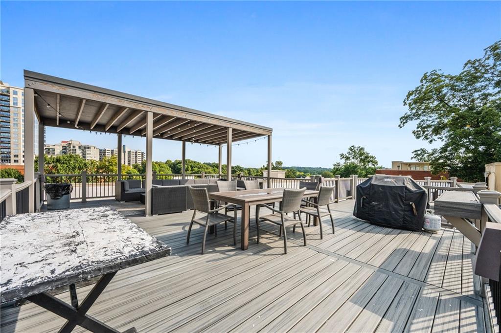 1029 Piedmont Avenue Northeast, Unit 303 Atlanta, GA 30309 - Photo 28 of 44 a view of a roof deck dining table and chairs under an umbrella with large trees