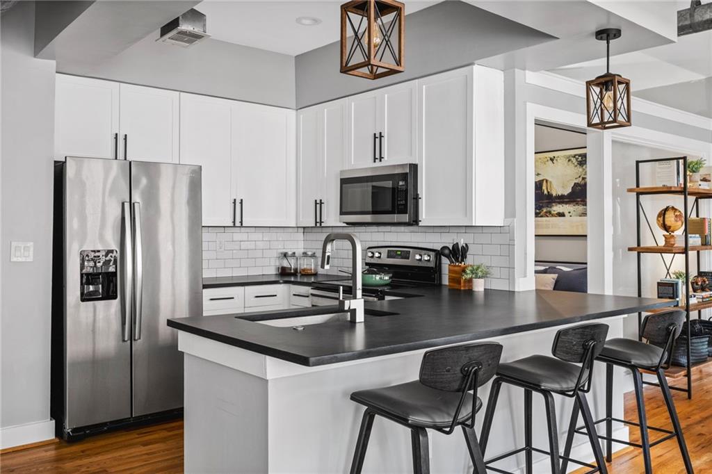 1029 Piedmont Avenue Northeast, Unit 303 Atlanta, GA 30309 - Photo 7 of 44 a kitchen with stainless steel appliances granite countertop a stove a refrigerator a sink a stove with island chairs and wooden cabinets