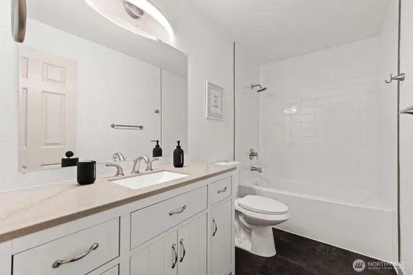 a bathroom with a granite countertop toilet a sink and a bathtub