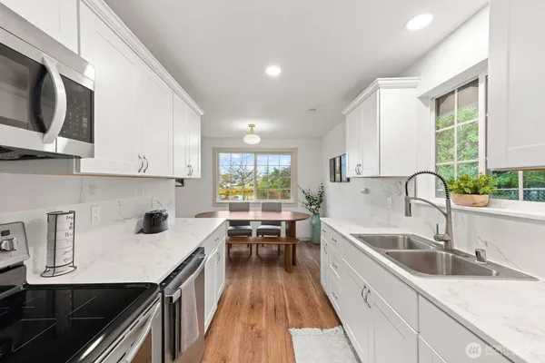 a kitchen with stainless steel appliances a sink a stove top oven a counter space and cabinets