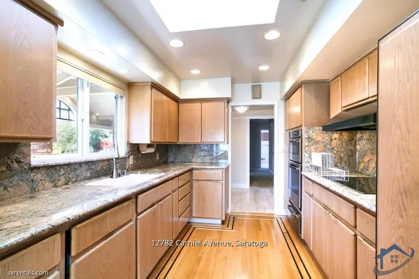 a large kitchen with stainless steel appliances granite countertop a large counter top a stove a sink and a refrigerator