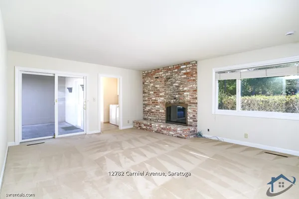 an empty room with windows and fireplace