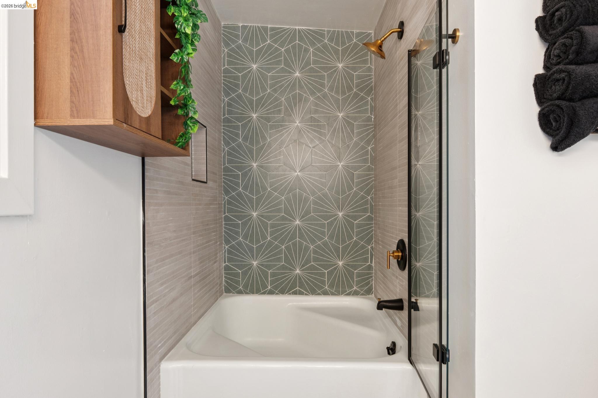 2301 Oak Street Berkeley, CA 94708 - Photo 58 of 61 Bathtub with geometric pattern tile surround, clear glass shower enclosure, and matte black and brass fixtures