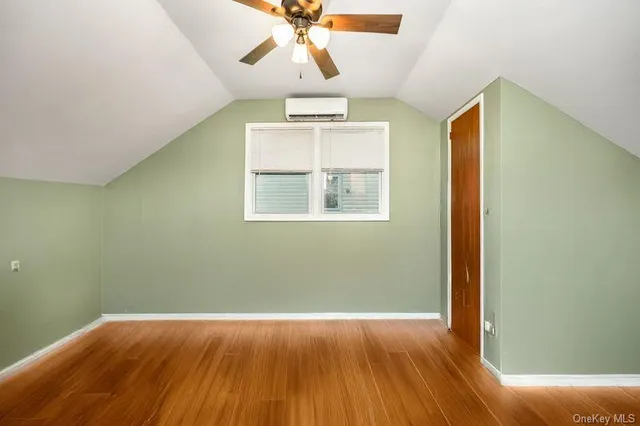 an empty room with wooden floor chandelier fan and windows