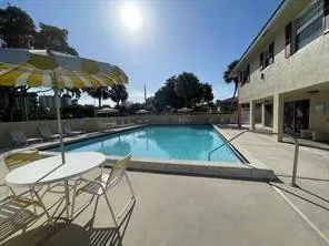 a view of swimming pool with chairs and umbrella