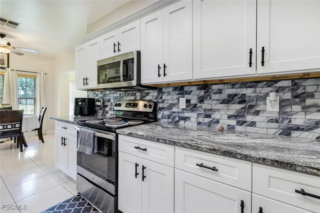 a kitchen with granite countertop white cabinets stainless steel appliances and a counter space