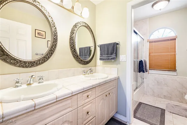 a bathroom with a granite countertop double vanity sink and a mirror