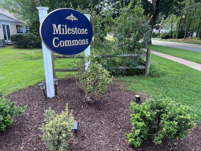 a sign that is sitting in the grass near a tree