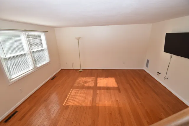 a view of an empty room with stairs and wooden floor