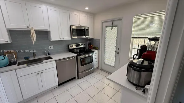 a kitchen with white cabinets and appliances