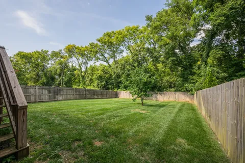 a backyard of a house with lots of plants and tree