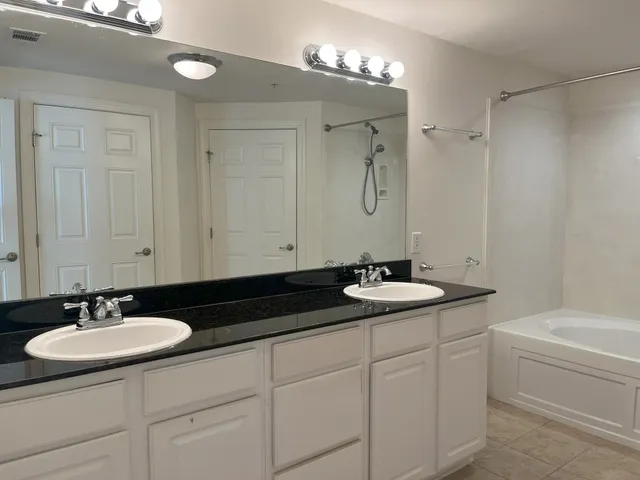 a white bath tub sitting next to a white sink and vanity