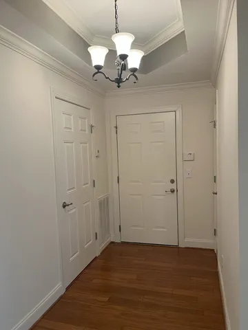 a view of an empty room with wooden floor and chandelier