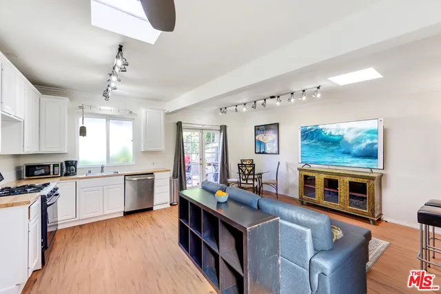 a kitchen with stainless steel appliances granite countertop a stove top oven a sink dishwasher and white cabinets with wooden floor