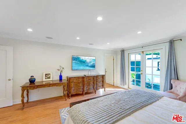 a spacious bedroom with a bed and a dresser with wooden floor