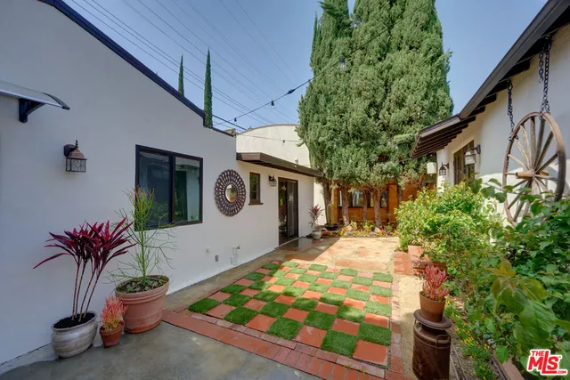 a vase of flowers sitting on a floor in front of a house