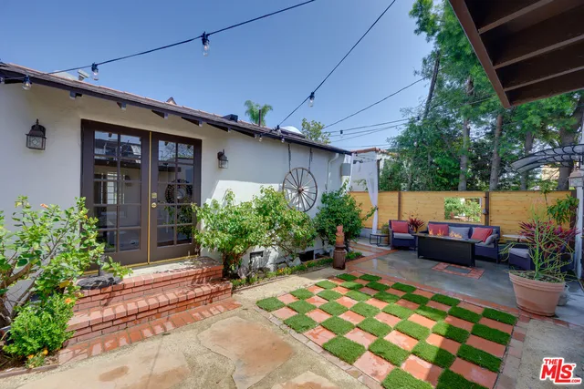 a backyard of a house with potted plants and large tree