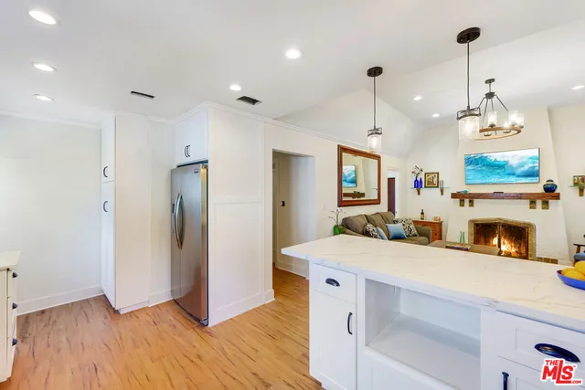 a kitchen with stainless steel appliances granite countertop a refrigerator a oven and a fireplace with wooden floor