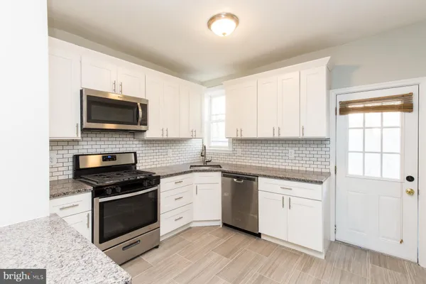 a kitchen with granite countertop a stove a sink and a microwave