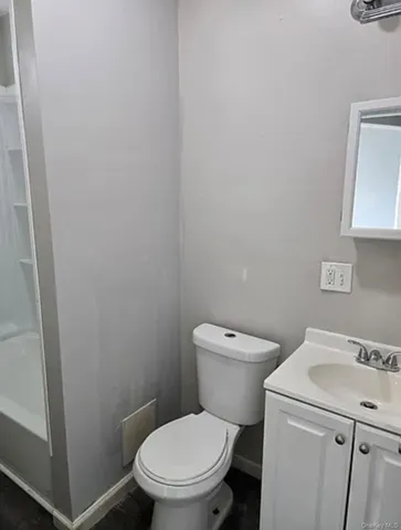 a white toilet sitting next to a white sink and vanity
