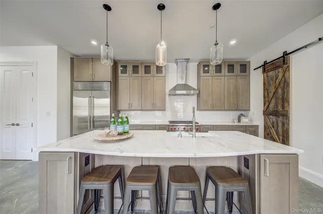 a kitchen with stainless steel appliances granite countertop a dining table chairs and white cabinets