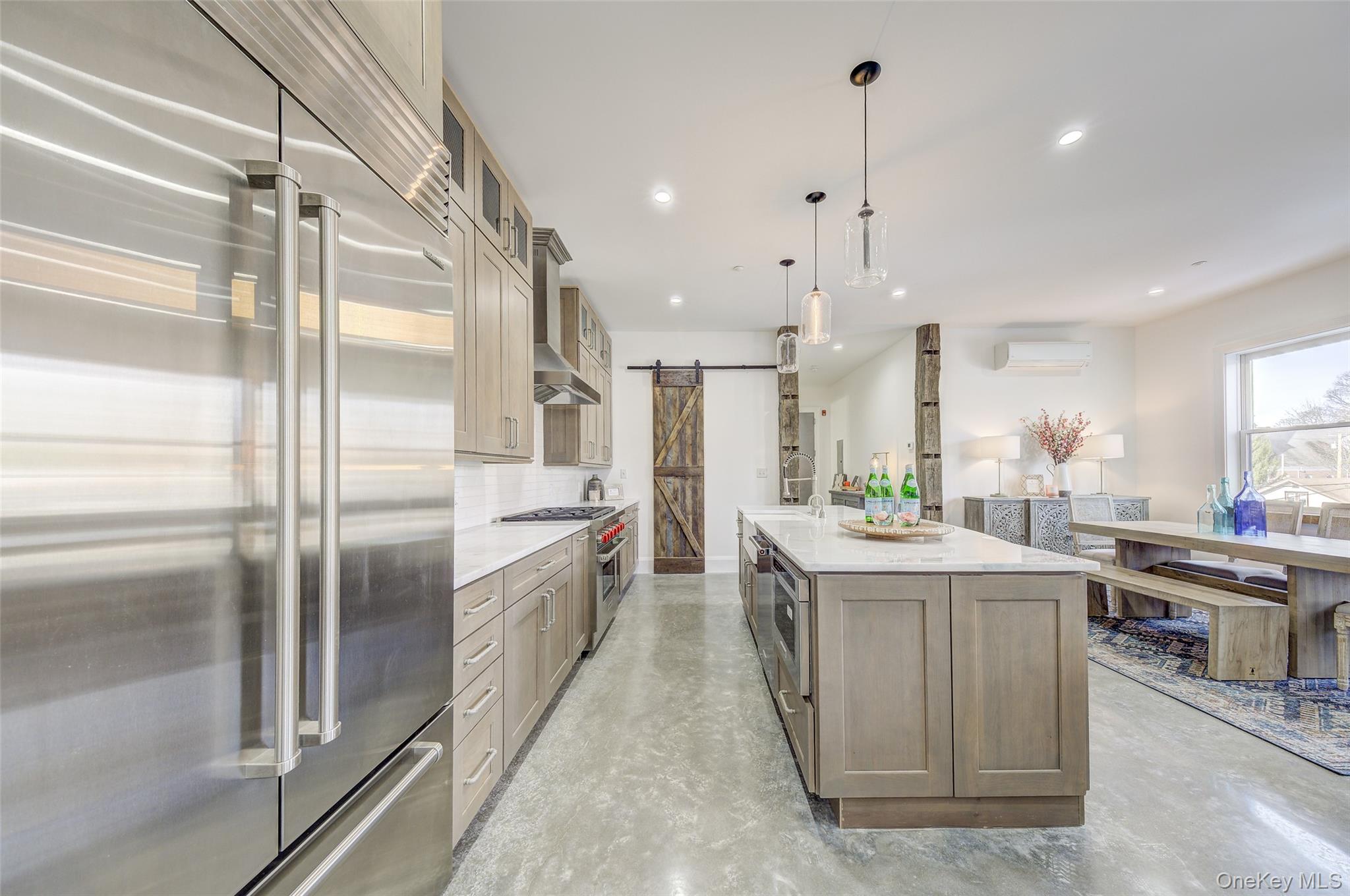 226 Main Street, Unit 302 Beacon, NY 12508 - Photo 14 of 43 Kitchen featuring premium appliances, a barn door, decorative backsplash, a center island with sink, and concrete flooring