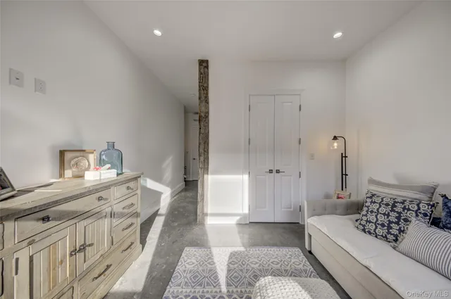 a spacious bedroom with a bed a rug and wooden floor